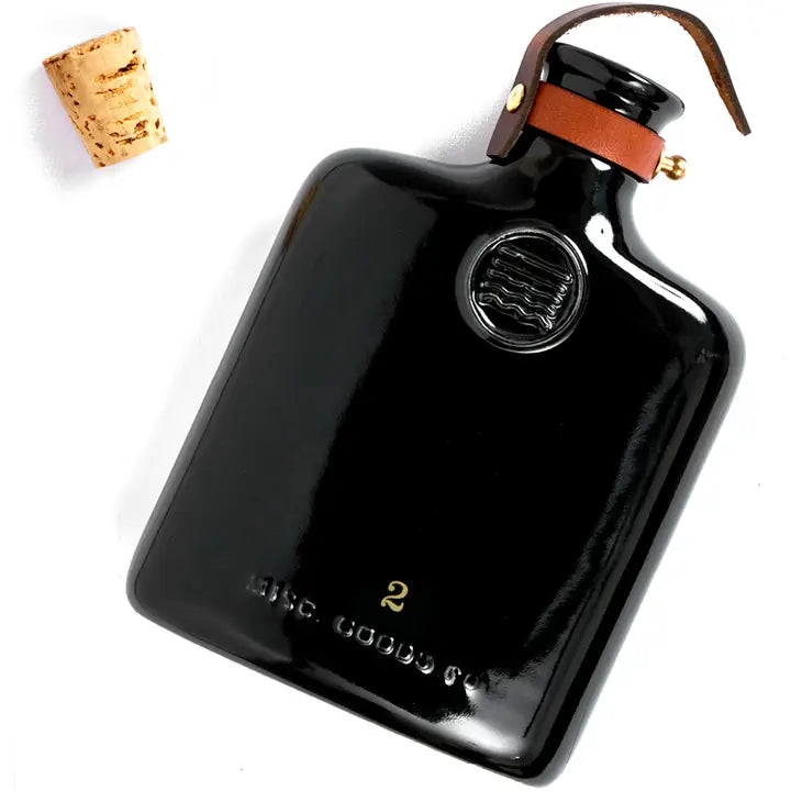 Classic ceramic flask inspired by the historic culture of distilling spirits, featuring intricate embossing, leather fastening, and brass hardware. Perfect for casual picnics, bar tops, or mantles.