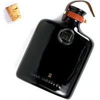 Classic ceramic flask inspired by the historic culture of distilling spirits, featuring intricate embossing, leather fastening, and brass hardware. Perfect for casual picnics, bar tops, or mantles.