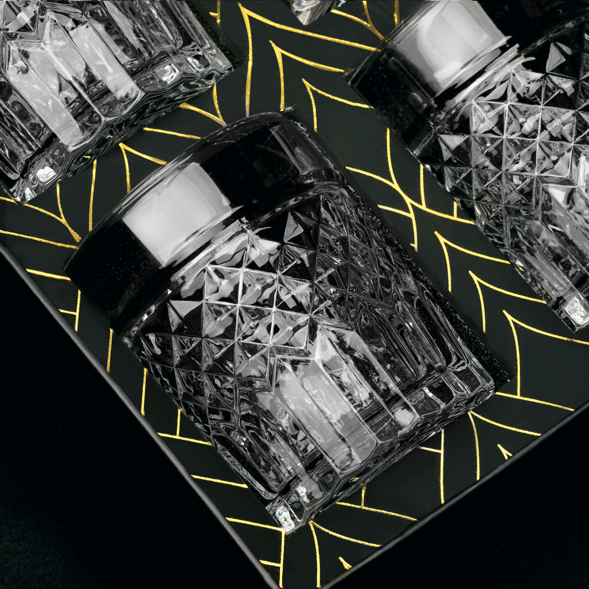 Close-up of black crystal whiskey glasses on an elegant patterned tray, perfect for cocktail enthusiasts.