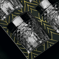 Close-up of black crystal whiskey glasses on an elegant patterned tray, perfect for cocktail enthusiasts.