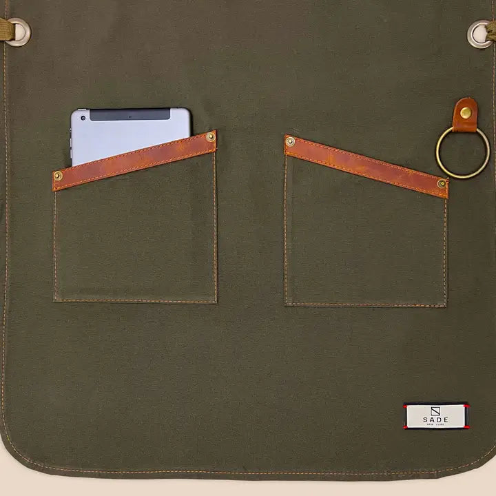 High-quality 100% cotton canvas apron with adjustable cross-back genuine leather straps for personalized fit, designed for comfort and durability in kitchens or workshops.