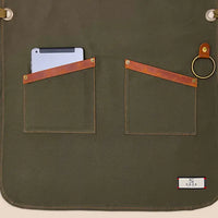High-quality 100% cotton canvas apron with adjustable cross-back genuine leather straps for personalized fit, designed for comfort and durability in kitchens or workshops.
