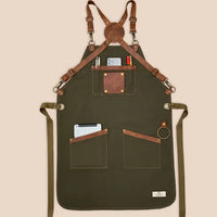 High-quality 100% cotton canvas apron with adjustable cross-back genuine leather straps for personalized fit, designed for comfort and durability in kitchens or workshops.