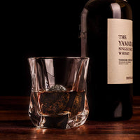 Twist glass with whiskey and a bottle of Yamazaki single malt, featuring whiskey chilling stones for the perfect drink.