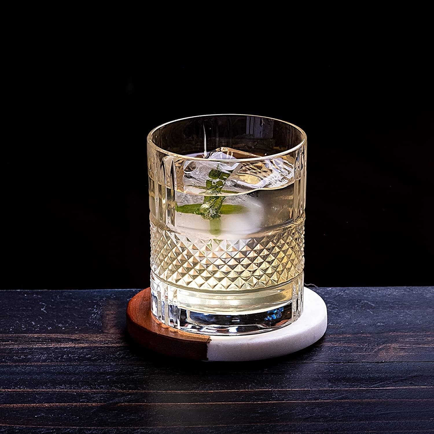 A stylish whiskey glass filled with a refreshing cocktail and ice, sitting on a modern coaster.