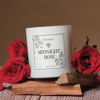 White candle labeled 'Midnight Rose' with red roses on a wooden surface