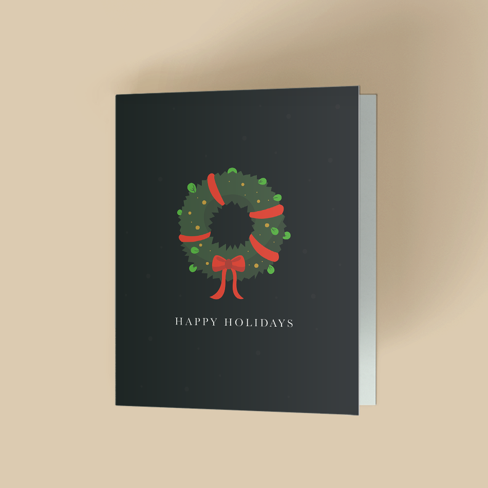 A dark green holiday greeting card featuring a festive winter wreath tied with a red ribbon at the bottom, centered above the text "HAPPY HOLIDAYS" in gold lettering, set against a warm beige background.