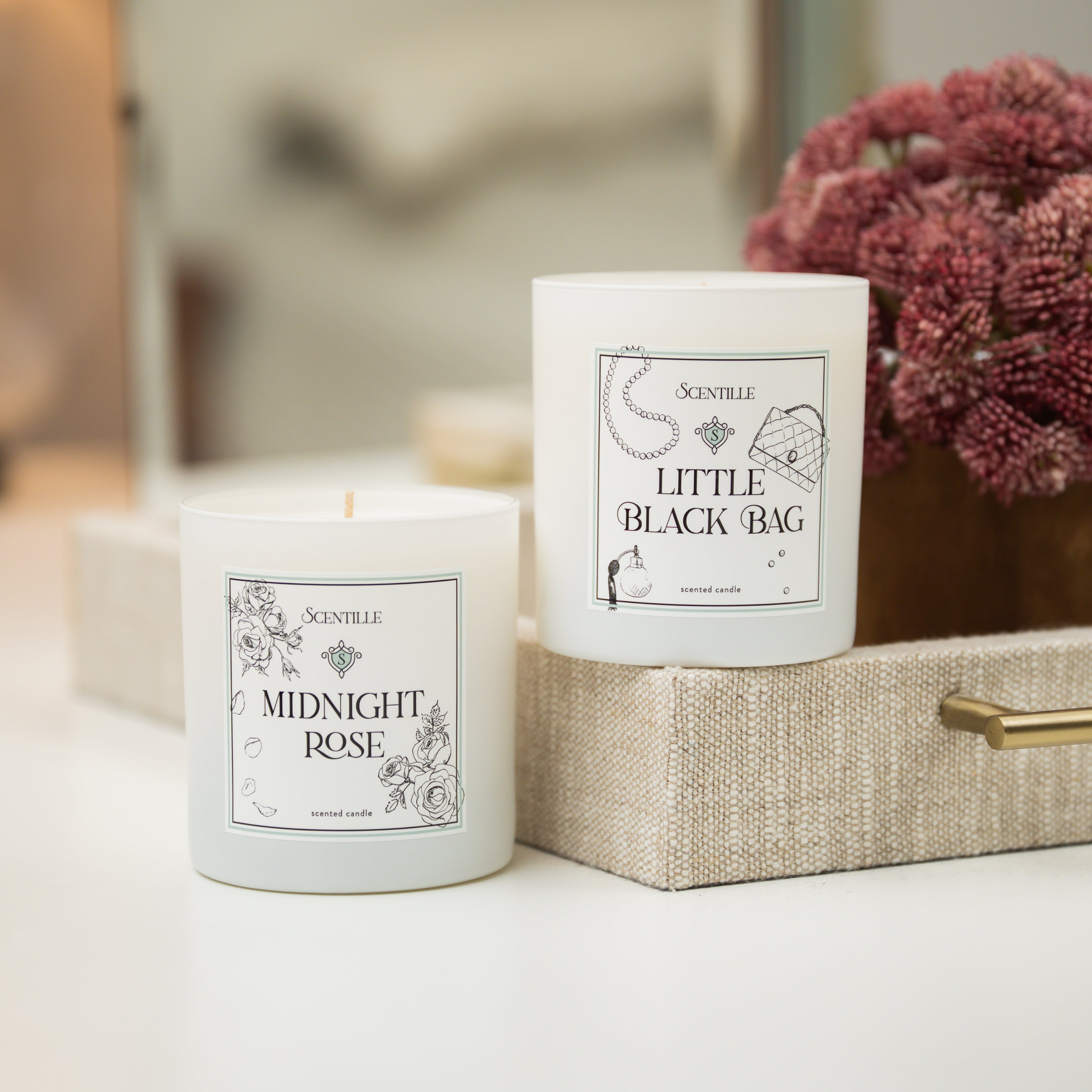 Two candles labeled 'Midnight Rose' and 'Little Black Bag' on a surface.